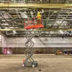 Skyjack SJ3219 scissor lift extended lifting operator to building ceiling.