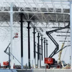 Skyjack SJ45 AJ+ boom lift raising materials and workers at a construction site.