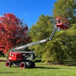 Skyjack SJ60 AJ+ articulating boom lift with partially raised jib in grass field.