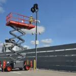 Skyjack SJ6826 rough terrain raised near light pole.