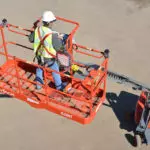 Operator in Skyjack SJ82/86 T telescopic boom lift on work site.