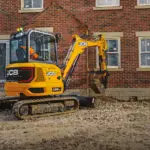 JCB 35z-1 compact excavator scooping dirt at construction site.