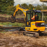 JCB 35z-1 compact excavator carrying materials at construction site.