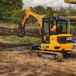JCB 35z-1 compact excavator carrying materials at construction site.