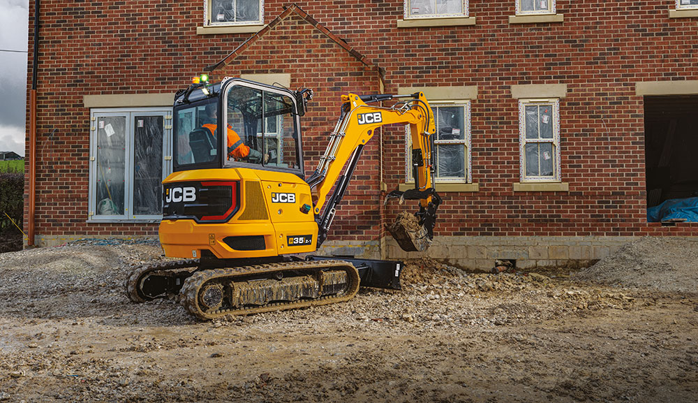 JCB 35z-1 compact excavator scooping dirt at construction site.