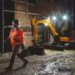 JCB 35z-1 compact excavator with lights on at dark construction site.