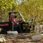 Pro XD Mid-Size Gas Utility Vehicle by Polaris Commercial driving up dirt hill on work site.