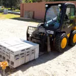 JCB 270W Skid Steer transporting pallet of bricks.
