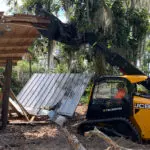 JCB 3TS-8T grabbing materials with attachment in forest area.