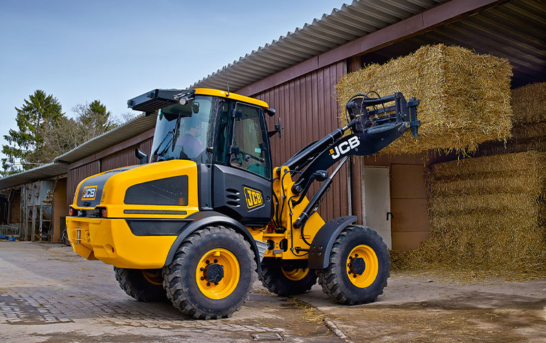 JCB 409 Wheel Loader stacking hay bails.