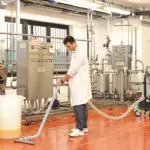 Nilfisk S2 vacuum with floor attachment on hose cleaning work area floor.