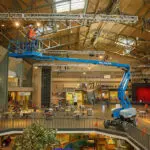 Genie Z-60 FE Articulating Boom Lift lifting operator indoors to replace a lightbulb.