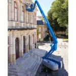 Workers in Genie S-60 DC Telescopic Boom Lift bucket working on the side of a building.