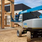 Back of Genie S-60 FE telescopic boom lift on dirt terrain at construction site.