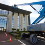 Genie S-60 FE telescopic boom lift lifting workers to building roof.
