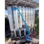 Genie S-80 J telescopic boom lift raising workers to build a new building.