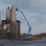 Genie S-80 J TraX telescopic boom lift lifting workers at outside site.