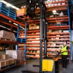 TASK Forklifts Viper reach truck grabbing a pallet of boxes off a shelf in a warehouse.