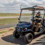 Cushman Hauler 1200 Utility Vehicle with trailer driving on path.