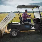 Cushman Hauler 1200X utility vehicle lifting bed to dump out dirt.