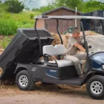 Cushman Hauler Pro utility vehicle lifting bed to dump out dirt.
