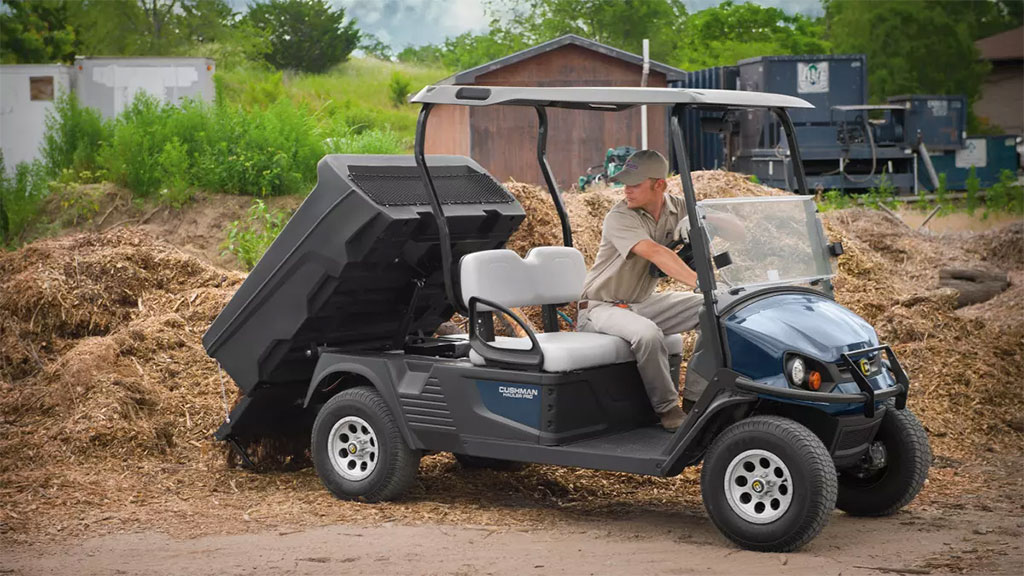 Cushman Hauler Pro utility vehicle lifting bed to dump out dirt.