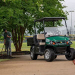 Man doing maintenance next to Cushman Hauler Pro utility vehicle.