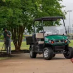 Man doing maintenance next to Cushman Hauler Pro utility vehicle.