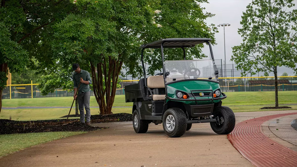 Man doing maintenance next to Cushman Hauler Pro utility vehicle.