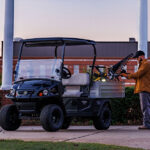 Worker putting tools in Cushman Hauler Pro utility vehicle cargo bed.
