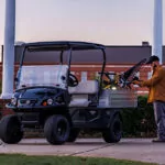 Worker putting tools in Cushman Hauler Pro utility vehicle cargo bed.