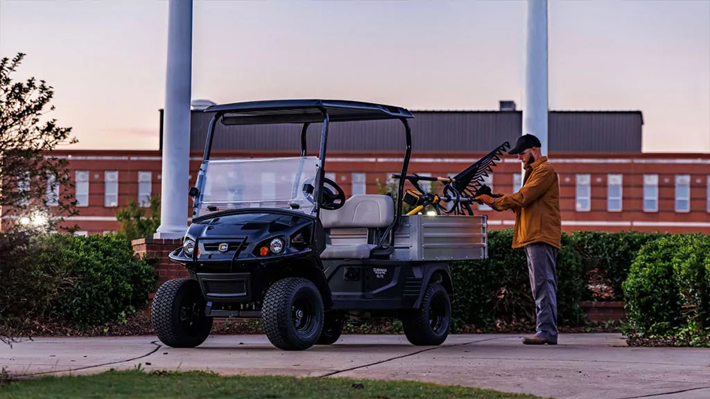 Worker putting tools in Cushman Hauler Pro utility vehicle cargo bed.