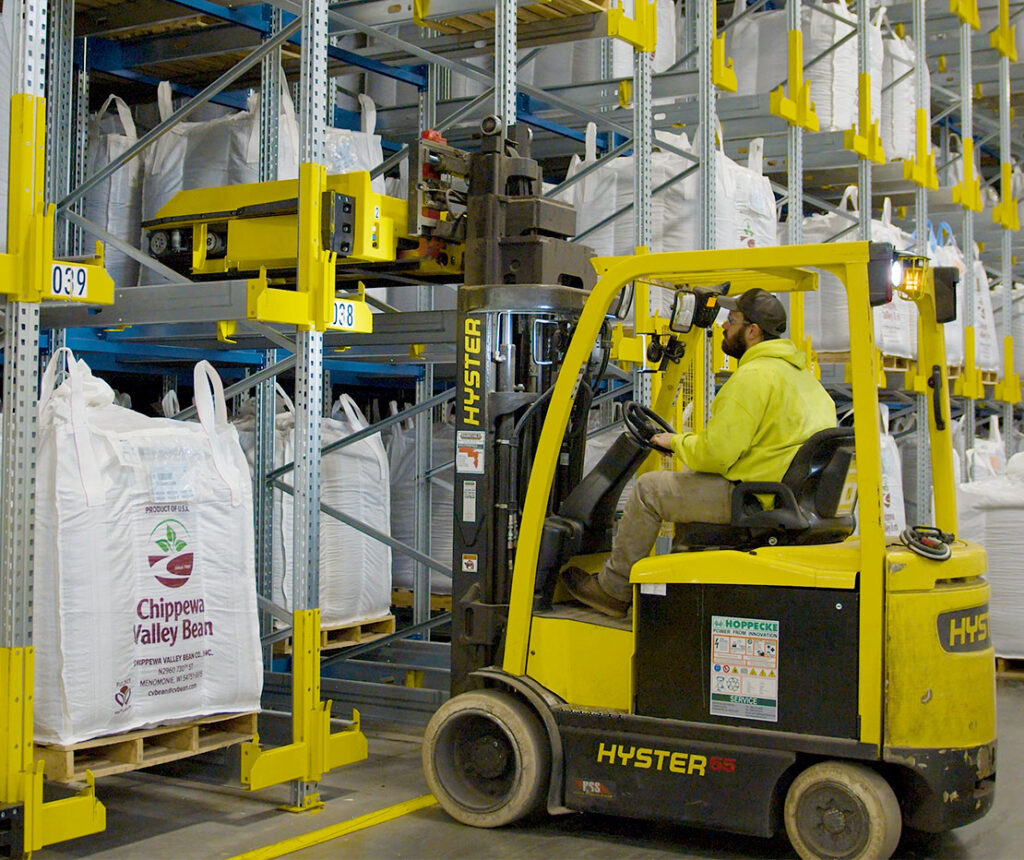Hyster E55 electric forklift grabbing SSI orbiter vehicle system off racking storage channel.