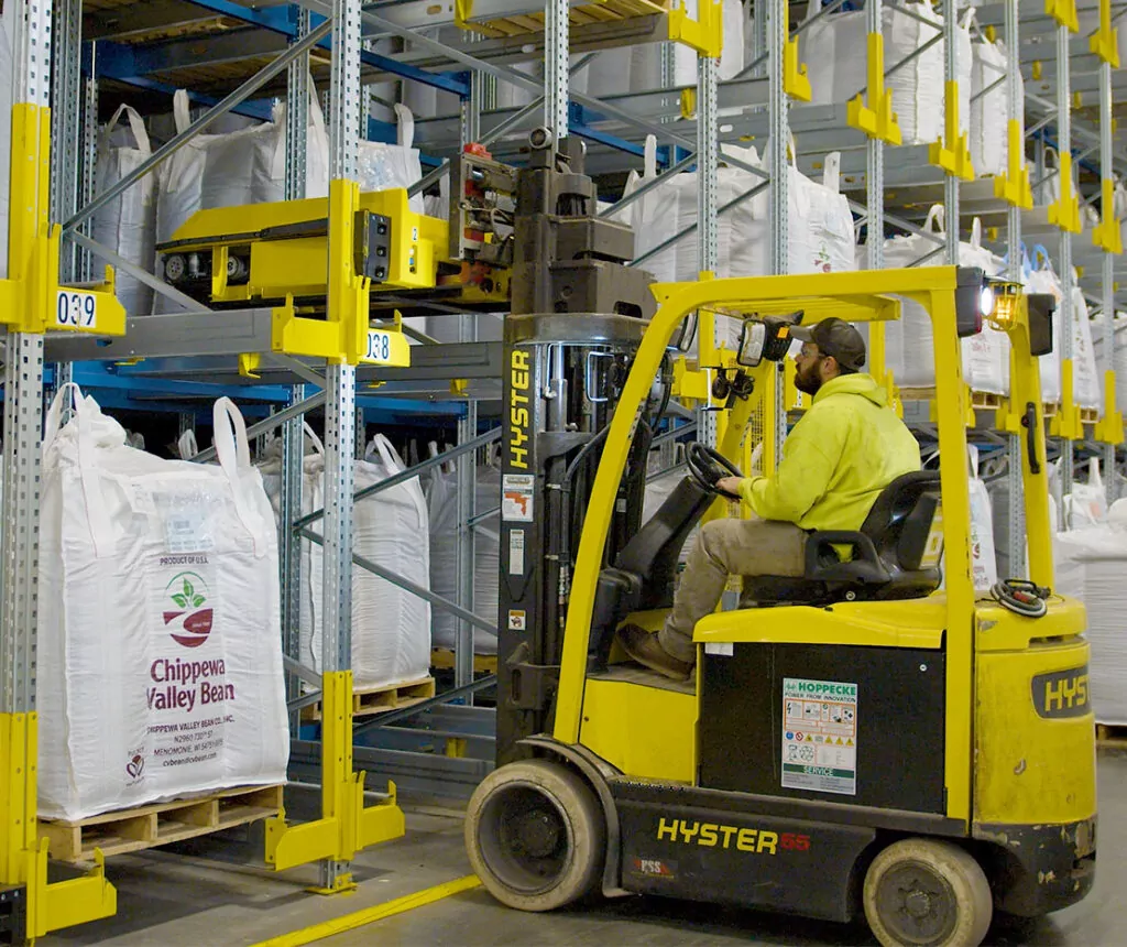 Hyster E55 electric forklift grabbing SSI orbiter vehicle system off racking storage channel.