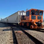 Rail King RK460 G7 railcar mover transporting several railcars on train tracks.