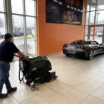 Kodiak K19 walk-behind scrubber with cylindrical deck cleaning automotive showroom.