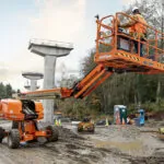 JLG 670SJ telescopic boom lift with bucket raised at outdoor worksite.