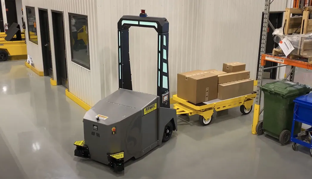 Automated Guided Vehicle Tow Tractor pulling a flat deck cart.