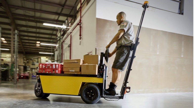 Employee riding stock chaser through warehouse.