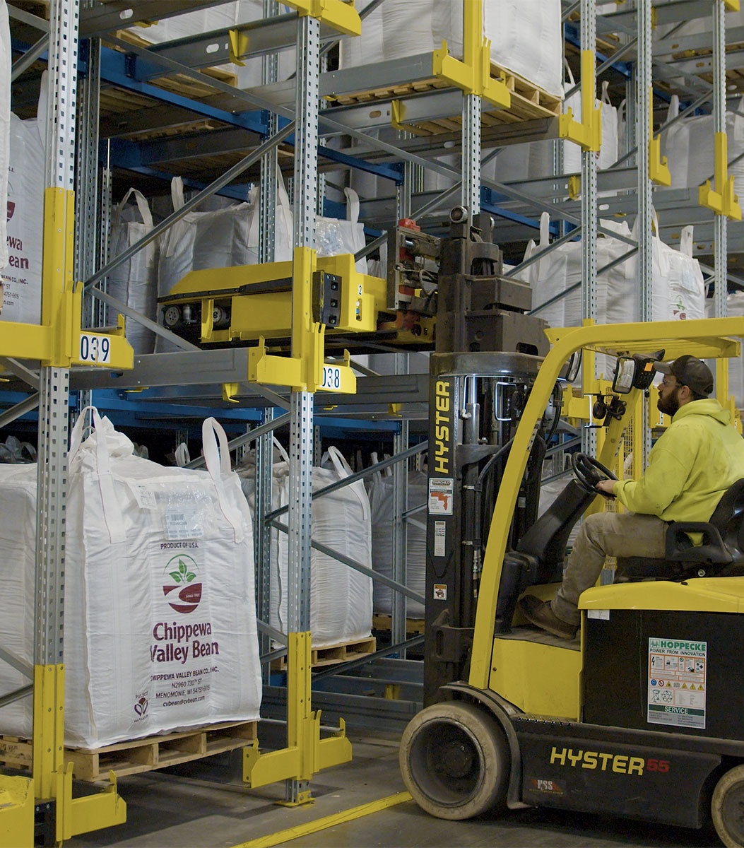 Hyster lift truck placing pallet shuttle on warehouse racking.