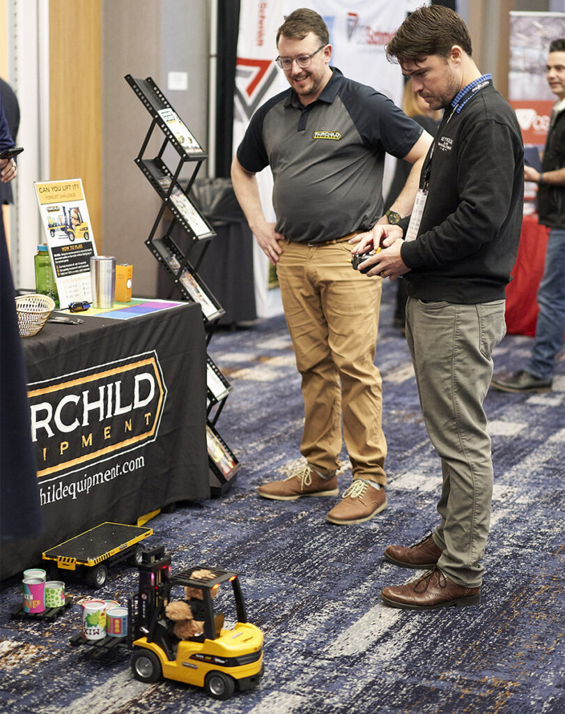 Fairchild Equipment Manager, TJ Ball, with event attendee completing the remote-controlled forklift challenge.