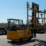 Drexel SL120 electric forklift transporting long load outdoors.
