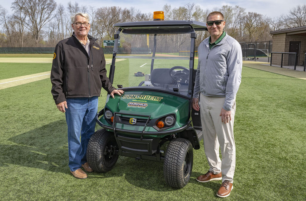 Chad and Gary Fairchild standing by St. Norbert's Cushman vehicle.