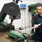 Nilfisk VHB436 Industrial Vacuum sucking up debris from machine work area in manufacturing facility.