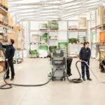 Nilfisk VHB436 Industrial Vacuum with two hose attachments cleaning warehouse facility.