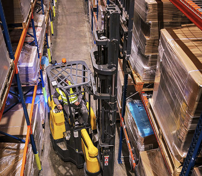 Combilift AC Electric Aisle Master lifting a pallet of goods off a warehouse rack.