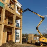 JCB AJ48D articulated boom lift raised at construction jobsite.