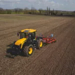 JCB 4220 Fastrac Icon agricultural tractor doing farmwork in large field.
